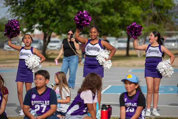 Three Bonillas cheerleaders cheer on their classmates on the kickball field