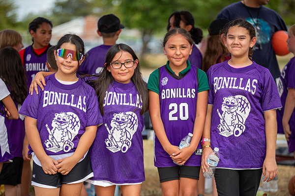 Four girls in purple Bonillas jerseys smile after the kickball game