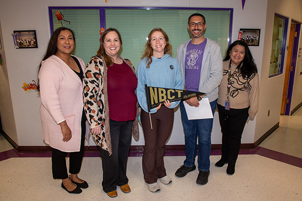 A woman, center, holds an NBCT pennant surrounded by her colleagues