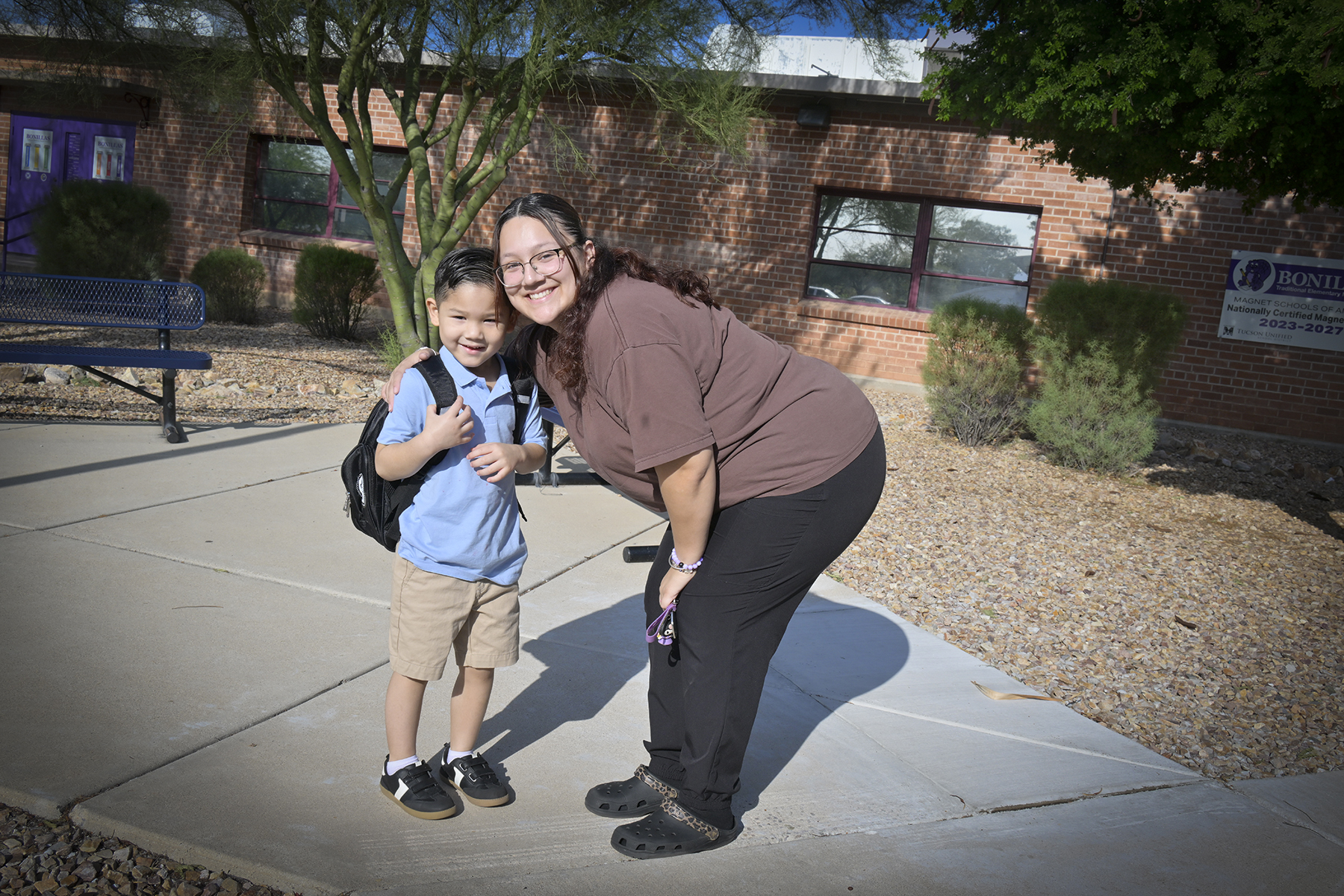 A mom and her son smile outside school